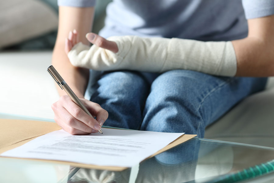 person writing with broken hand applying for Group Benefits in McAllen.