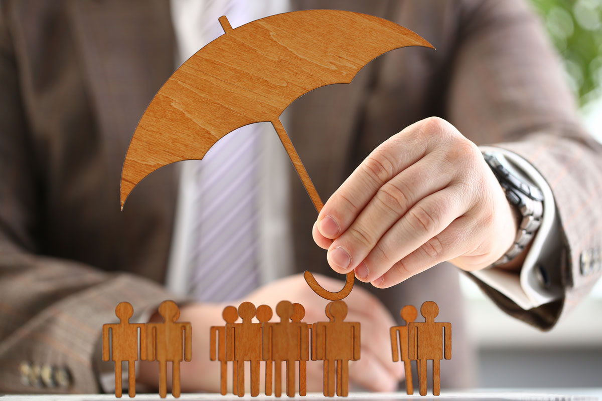 Businessman holds group benefits plans umbrella in hand over many people.